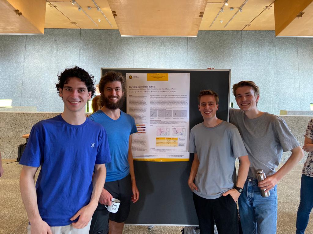 The four of us standing beside our poster at the course poster session